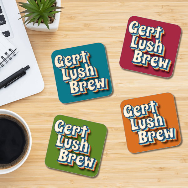 A set of square coasters with a retro style 'Gert Lush Brew' print, displayed on a wooden surface with a cup of coffee and a pen in the background.